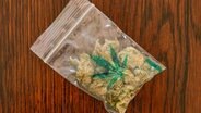Ein Beutel mit einer Cannabis-Blüte liegt auf einem Tisch. © picture alliance / Bildagentur-online/Joko 